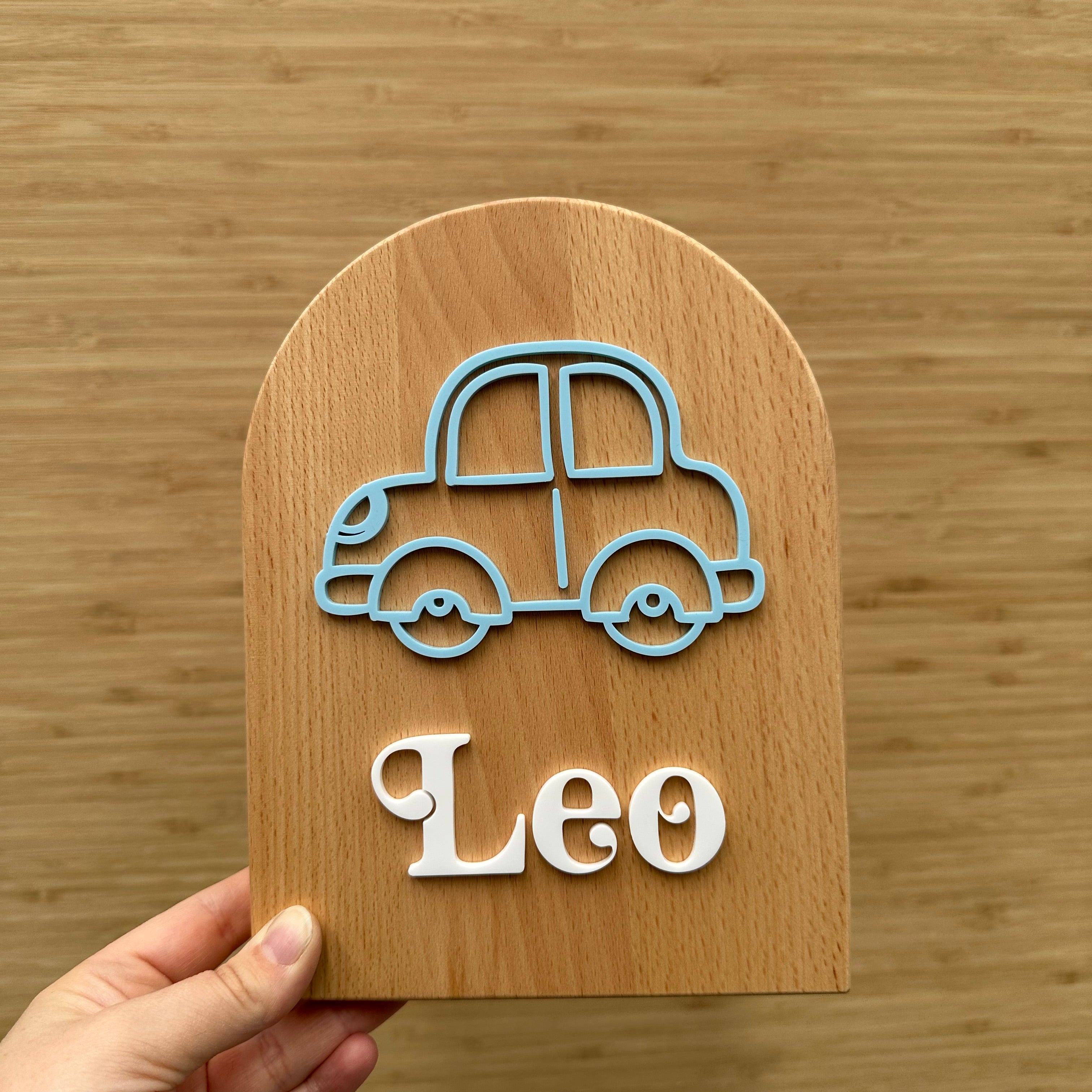 A child's money box in an arch shapee with a car design on  it, personalised with a child's name, blue and white