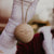 A person holding up a single wooden Christmas bauble with the name 'TIANA' engraved on it.